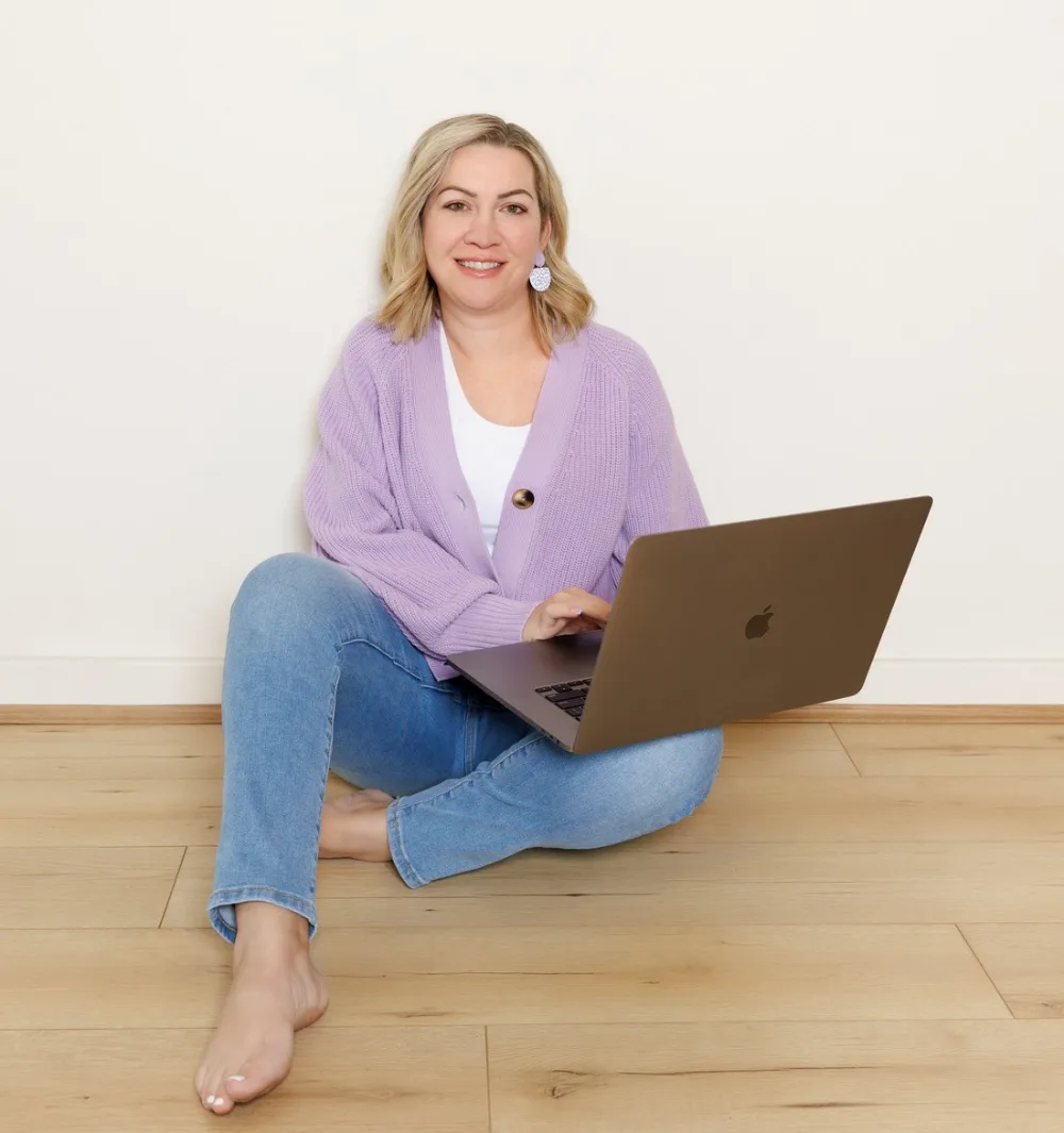 Carly sitting on the floor working on her laptop, laughing